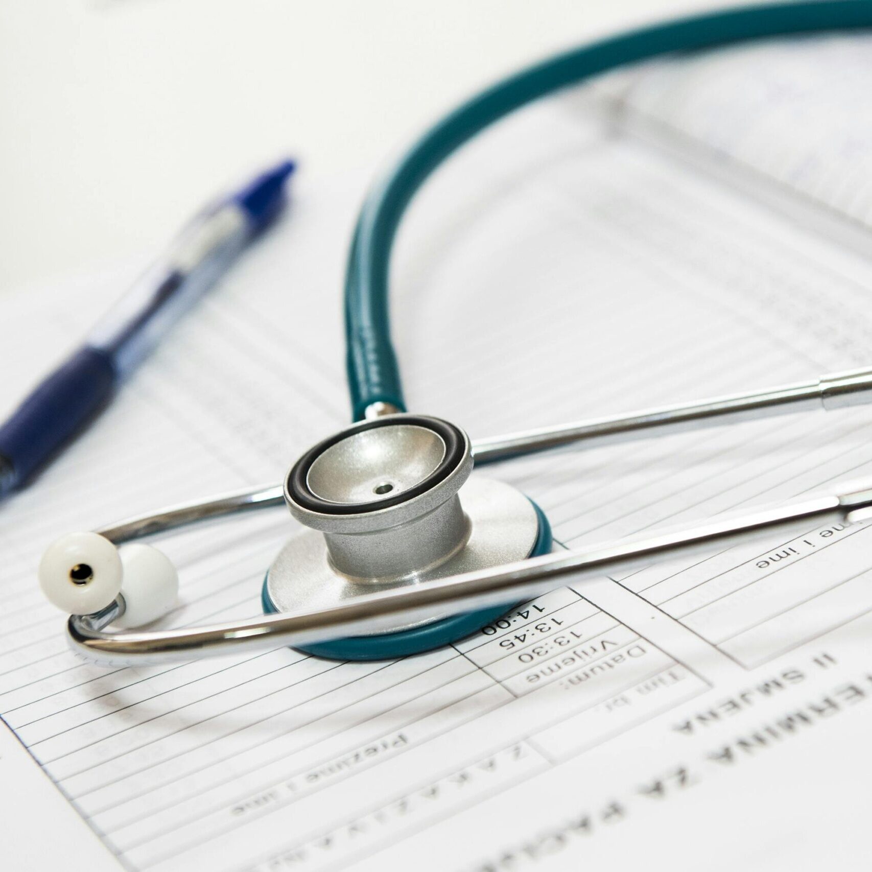 A stethoscope and pen resting on a medical report in a healthcare setting.