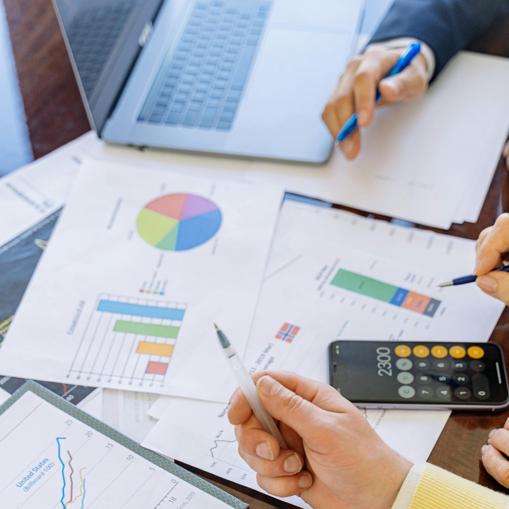 A close-up of businesspeople analyzing financial data and charts during a meeting.